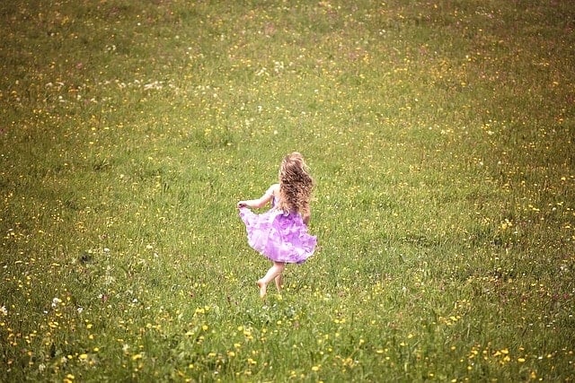 広大な草原を走っている幼い少女。